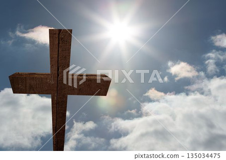 Rough wooden cross is rising in flat design against bright blue sky with lens flare, clouds Rough wooden cross is rising in flat design against bright blue sky with lens flare, clouds 135034475