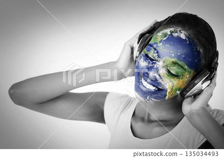 Woman is wearing over-ear headphones and showing world map face paint in studio portrait Woman is wearing over-ear headphones and showing world map face paint in studio portrait 135034493