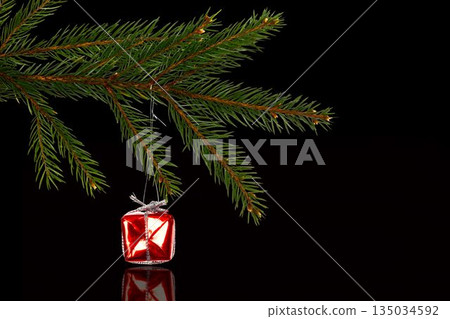 Small red gift box with silver ribbon is hanging from pine branch in 3D-rendered reflective scene Small red gift box with silver ribbon is hanging from pine branch in 3D-rendered reflective scene 135034592