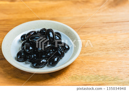 Black beans served in a small plate on a wooden table 135034948