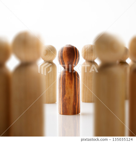 Wooden peg dolls, with one distinct figure standing out from the crowd. Symbolizing individuality, leadership, uniqueness, or standing out from the crowd. Concept of uniqueness 135035124