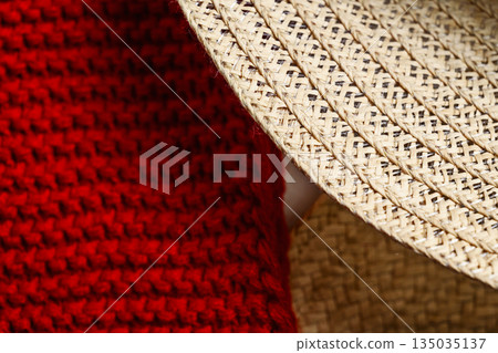 Closeup view showing the detail and texture of a woven straw hat and a red knitted fabric. The focus is on the intricate patterns and materials Closeup view showing the detail and texture of a woven straw hat and a red knitted fabric. The focus is on the intricate patterns and materials 135035137