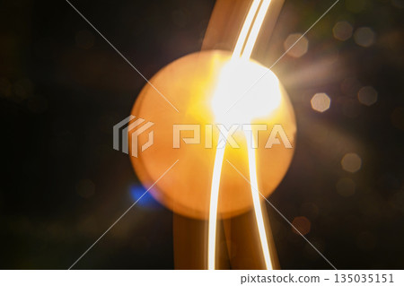 Abstract image featuring flowing light trails, creating curved lines with a warm, glowing tone. The light paints an organic, dynamic texture against a dark background Abstract image featuring flowing light trails, creating curved lines with a warm, glowing tone. The light paints an organic, dynamic texture against a dark background 135035151
