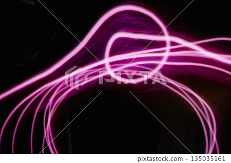 Abstract image of pink neon light painting in a circular and spiral pattern against a black background. A modern and futuristic design element Abstract image of pink neon light painting in a circular and spiral pattern against a black background. A modern and futuristic design element 135035161