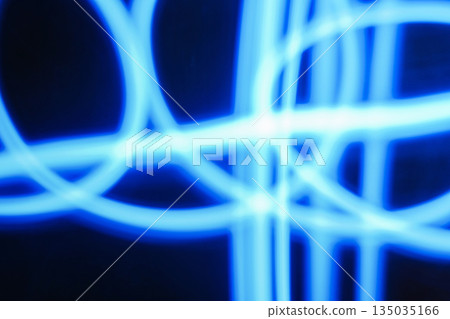 Abstract image of blue neon light painting in a circular and spiral pattern against a black background. A modern and futuristic design element 135035166