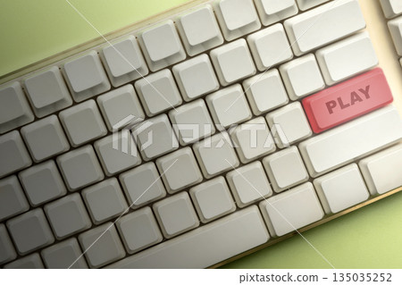 Closeup view of a computer keyboard with a red button that says "Play". Great for technology, game, or entertainment concepts 135035252