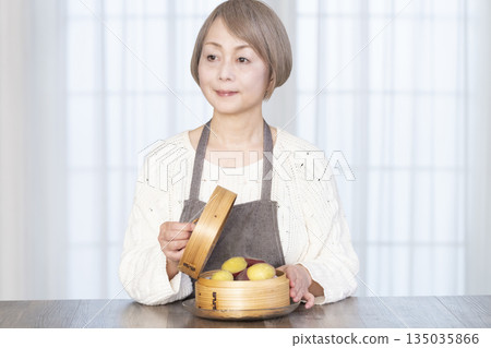 一位老婦人正在用竹蒸籠蒸地瓜。 135035866