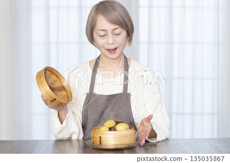 一位老婦人正在用竹蒸籠蒸地瓜。 一位老婦人正在用竹蒸籠蒸地瓜。 135035867