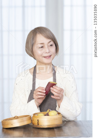 一位老婦人正在用竹蒸籠蒸地瓜。 一位老婦人正在用竹蒸籠蒸地瓜。 135035890