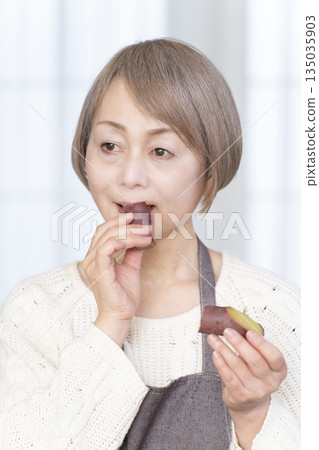 Senior woman eating steamed sweet potato in a bamboo steamer Senior woman eating steamed sweet potato in a bamboo steamer 135035903