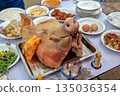 A cultural ritual table with a boiled pig's head, eggs, vegetables, and traditional offerings. 135036354