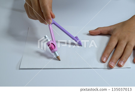特寫鏡頭:一隻孩子的手用圓規畫圓。 特寫鏡頭:一隻孩子的手用圓規畫圓。 135037013