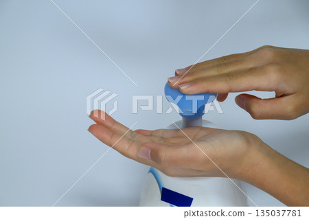 Hands dispensing sanitizer or soap from a pump bottle 135037781