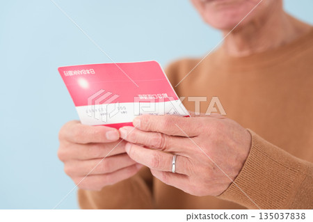 Senior man looking at his bankbook and worrying Senior man looking at his bankbook and worrying 135037838