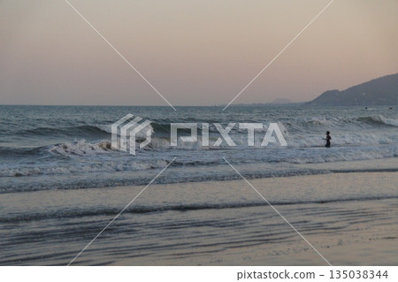 Sea waves at sunset.Child playing with sea waves at sunset. 135038344