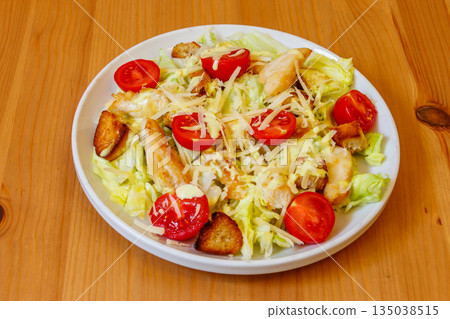 Fresh healthy caesar salad with chicken breast, cherry tomatoes, lettuce, parmesan cheese, dressing and croutons on wooden table Fresh healthy caesar salad with chicken breast, cherry tomatoes, lettuce, parmesan cheese, dressing and croutons on wooden table 135038515