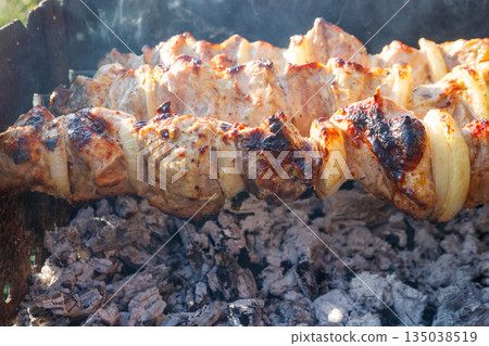 Grilled kebab cooking on metal skewer. Roasted meat cooked at barbecue.Traditional eastern dish, shish kebab. Grill on charcoal and flame, picnic, street food 135038519