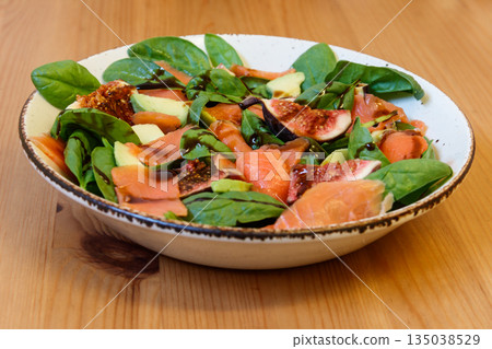Healthy salad with smoked salmon, spinach, avocado and fig on wooden table Healthy salad with smoked salmon, spinach, avocado and fig on wooden table 135038529