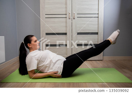 Woman performing V-sit exercise on yoga mat indoors, focus on core strength and abdominal muscles training, fitness routine at home for healthy lifestyle Woman performing V-sit exercise on yoga mat indoors, focus on core strength and abdominal muscles training, fitness routine at home for healthy lifestyle 135039092