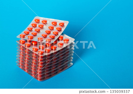 Stack of blisters of red pills on a blue background. Concept of medicines and vitamins in tablets. Copy space for text, healthcare 135039337