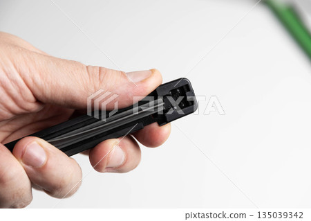 Close-up of human hand performing replacement of rubber element in car windshield wiper blade against clean white background Close-up of human hand performing replacement of rubber element in car windshield wiper blade against clean white background 135039342
