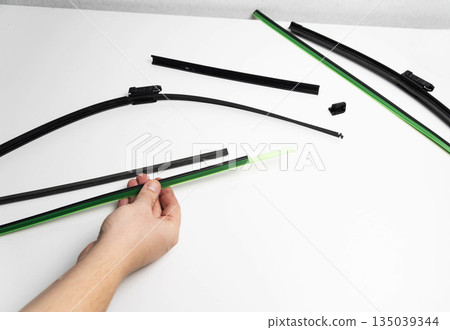 Hand of person replacing rubber blade element of car windshield wiper on white background, maintenance process for vehicle component Hand of person replacing rubber blade element of car windshield wiper on white background, maintenance process for vehicle component 135039344