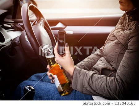 Irresponsible Driver Holds Alcohol And Breath Tester In Vehicle. Don't Drink And Drive Concept. Driving license revocation for alcohol 135040163
