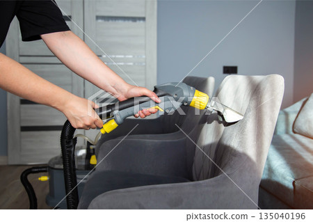 Cleaning process of a fabric chair using a steam cleaner in a modern living room setting Cleaning process of a fabric chair using a steam cleaner in a modern living room setting 135040196