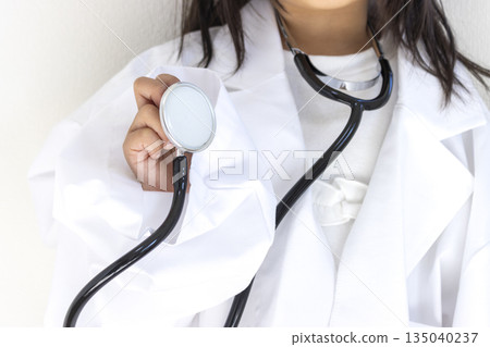 一名5歲日本女孩(未露臉)身穿成人尺寸的大號白大褂,手持聽診器 一名5歲日本女孩(未露臉)身穿成人尺寸的大號白大褂,手持聽診器 135040237