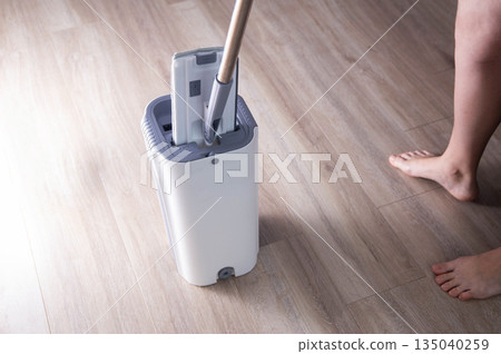 Washing and cleaning the room with a modern mop with a bucket and wringer. Modern novelty for cleaning. Copy space for text, industry Washing and cleaning the room with a modern mop with a bucket and wringer. Modern novelty for cleaning. Copy space for text, industry 135040259