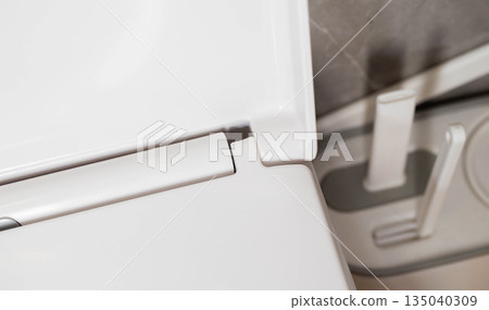 Broken hinge on white toilet seat and lid, close-up, industry, low quality plastic Broken hinge on white toilet seat and lid, close-up, industry, low quality plastic 135040309