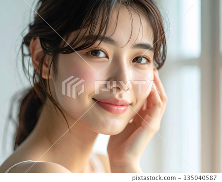 Smiling young woman with her hand on her cheek 135040587