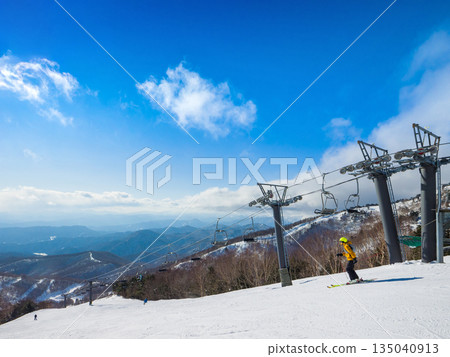 Winter scenery with ski lift posts and skiers sliding down the slopes (Kawaba, Gunma Prefecture) 135040913