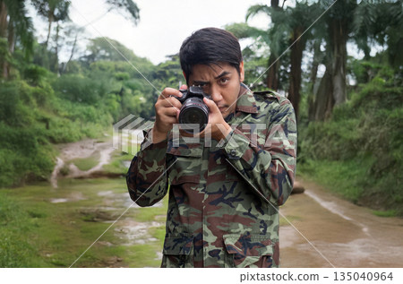 Asian man in a military uniform is capturing the beauty of nature with a DSLR camera 135040964