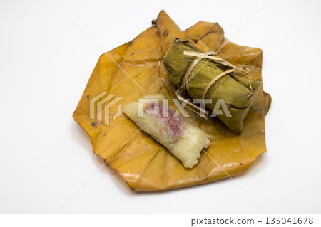 Khao Tom Mat (Thai Sticky Rice with Banana): A traditional Thai dessert made from seasoned sticky rice and coconut milk, filled with banana, and beautifully wrapped in a banana leaf 135041678