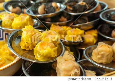 pork shumai, artfully arranged in a small bowl, ready to serve from a traditional bamboo steamer in an authentic Asian kitchen setting 135041681