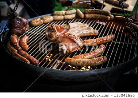 Smoked pork knuckle and grilled sausages on a barbecue grill, perfect for a hearty meal. Delicious, savory 135041686