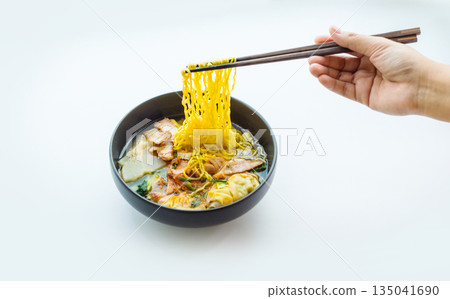 Hand picking yellow noodles from a pork noodle bowl on a white background for advertising Hand picking yellow noodles from a pork noodle bowl on a white background for advertising 135041690