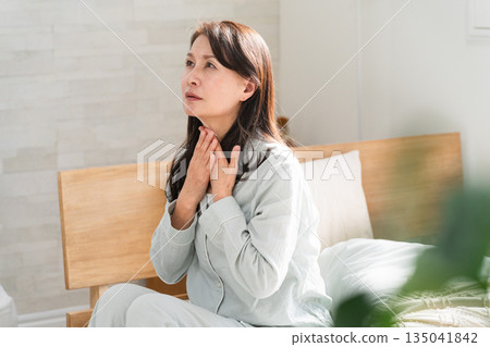 A woman wakes up in bed and complains of a sore throat 135041842