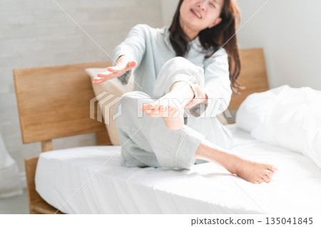 A woman wakes up in bed with cramps in her legs 135041845