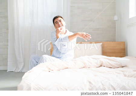 A man wakes up and stretches on his bed A man wakes up and stretches on his bed 135041847