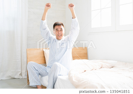 An energetic man waking up and pumping his fist in bed An energetic man waking up and pumping his fist in bed 135041851