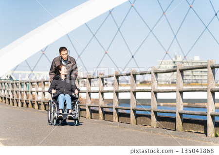 一對中年夫婦推著輪椅四處走動 一對中年夫婦推著輪椅四處走動 135041868