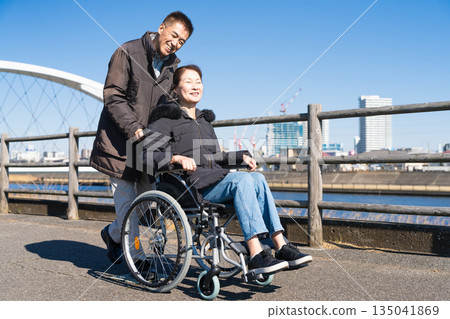 一對中年夫婦推著輪椅四處走動 一對中年夫婦推著輪椅四處走動 135041869