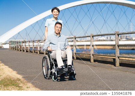 一名男子和他的護理人員推著輪椅四處走動 一名男子和他的護理人員推著輪椅四處走動 135041876