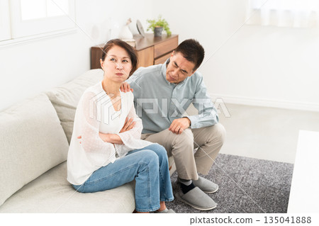 Mature couple sitting on sofa Mature couple sitting on sofa 135041888