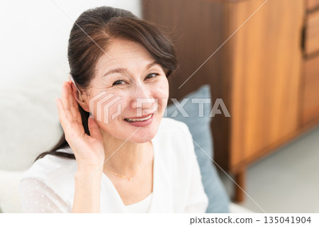 Mature woman wearing a hearing aid Mature woman wearing a hearing aid 135041904