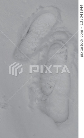 Footprints in fresh snow showing clear shoe tread pattern on winter surface. This image represents journey movement and traces of human presence in nature Footprints in fresh snow showing clear shoe tread pattern on winter surface. This image represents journey movement and traces of human presence in nature 135041944