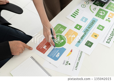 A diverse business team analyzing environmental charts and graphs in a collaborative meeting to create sustainable strategies in a modern office. A diverse business team analyzing environmental charts and graphs in a collaborative meeting to create sustainable strategies in a modern office. 135042015