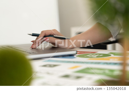 A diverse business team analyzing environmental charts and graphs in a collaborative meeting to create sustainable strategies in a modern office. 135042018